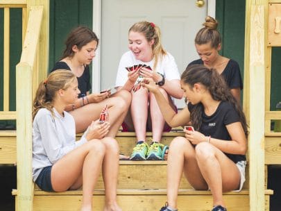 girls playing uno on the stairs of a cabin